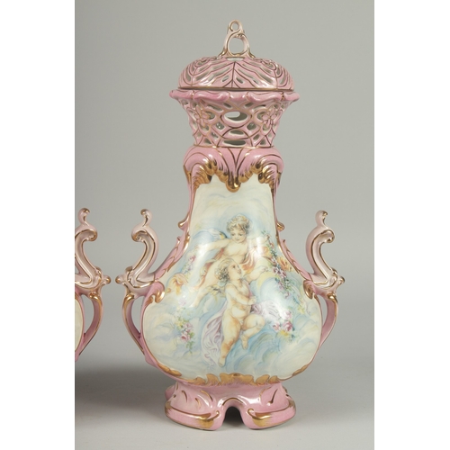 1084 - A PAIR OF SEVRES DESIGN PINK GROUND PORCELAIN VASES AND COVERS decorated with cupids. 15ins high.... 