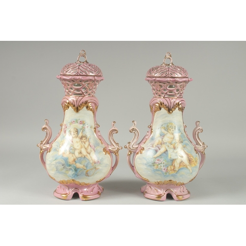 1084 - A PAIR OF SEVRES DESIGN PINK GROUND PORCELAIN VASES AND COVERS decorated with cupids. 15ins high.... 