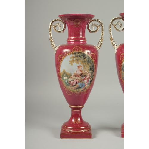 1085 - A PAIR OF SEVRES DESIGN RED GROUND PORCELAIN VASES AND COVERS decorated with reverse scenes of figur... 