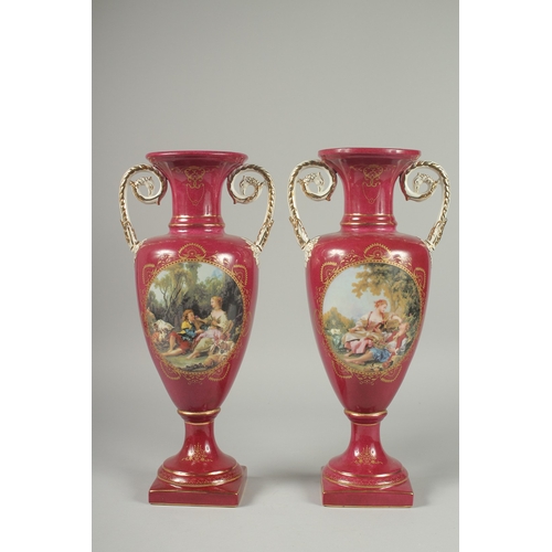 1085 - A PAIR OF SEVRES DESIGN RED GROUND PORCELAIN VASES AND COVERS decorated with reverse scenes of figur... 