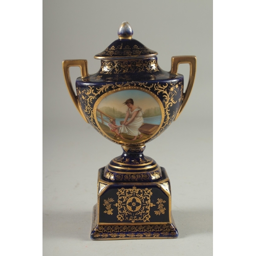 1091 - A SMALL VIENNA RICH BLUE GROUND TWO HANDLED URN AND COVER with a panel of a young lady with a cupid.... 