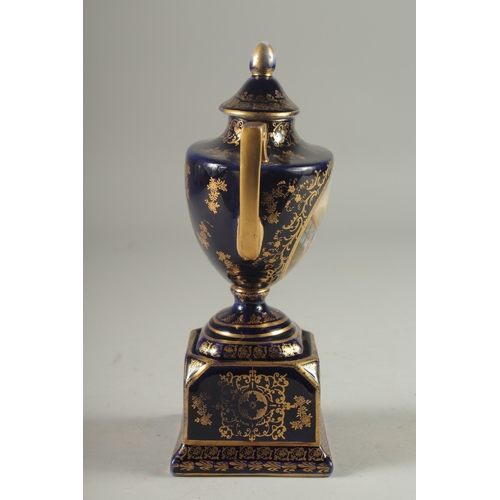 1091 - A SMALL VIENNA RICH BLUE GROUND TWO HANDLED URN AND COVER with a panel of a young lady with a cupid.... 