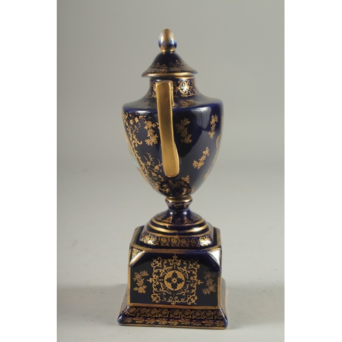 1091 - A SMALL VIENNA RICH BLUE GROUND TWO HANDLED URN AND COVER with a panel of a young lady with a cupid.... 