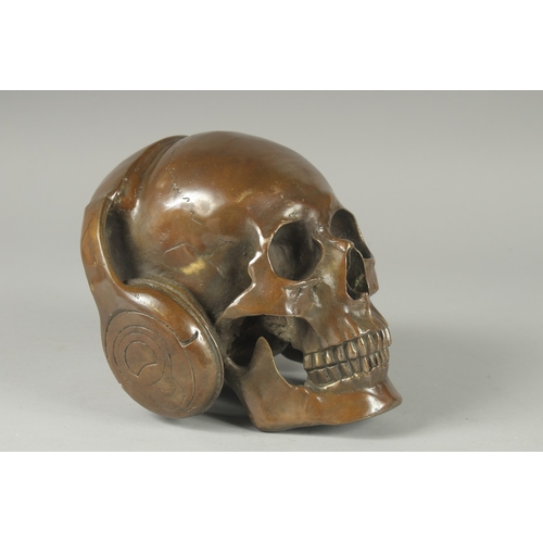 1116 - A BRONZE SKULL with headphones. 6ins high.