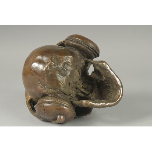 1116 - A BRONZE SKULL with headphones. 6ins high.