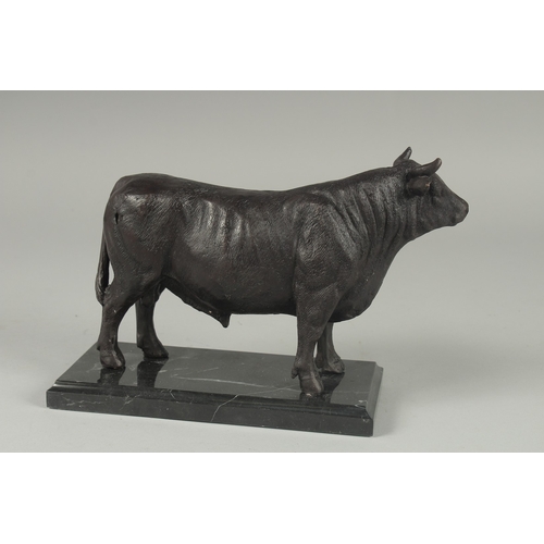 1121 - A BRONZE STANDING BULL on a marble base.  9.5ins long.