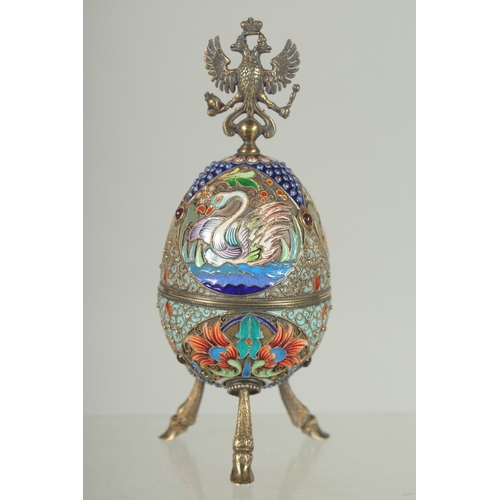 1423 - A LARGE RUSSIAN SILVER AND ENAMEL EGG on three curving feet. 12cm long 5cm diameter decorated with t... 