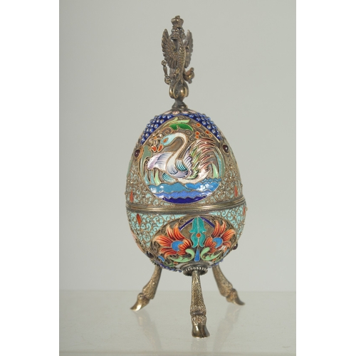 1423 - A LARGE RUSSIAN SILVER AND ENAMEL EGG on three curving feet. 12cm long 5cm diameter decorated with t... 