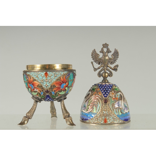 1423 - A LARGE RUSSIAN SILVER AND ENAMEL EGG on three curving feet. 12cm long 5cm diameter decorated with t... 