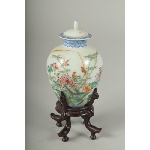 11 - A SMALL CHINESE REPUBLIC PERIOD PORCELAIN JAR AND COVER, on a fitted wooden stand, painted with bird... 