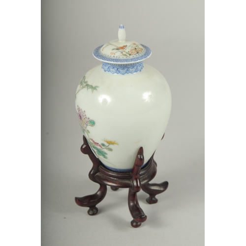 11 - A SMALL CHINESE REPUBLIC PERIOD PORCELAIN JAR AND COVER, on a fitted wooden stand, painted with bird... 