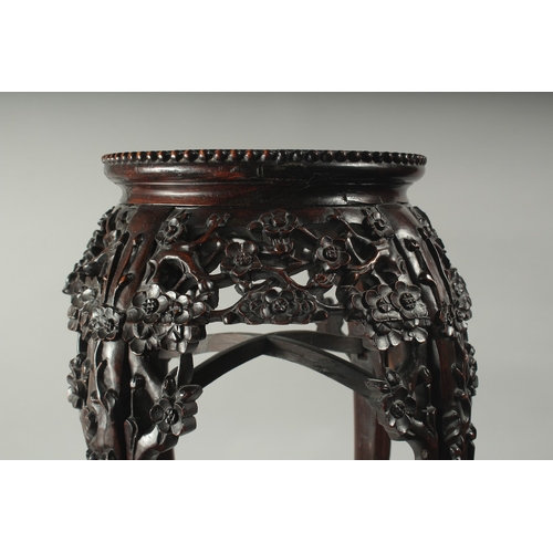 143 - A CHINESE MARBLE INSET CARVED HARDWOOD VASE STAND, with carved and pierced floral frieze on curving ... 