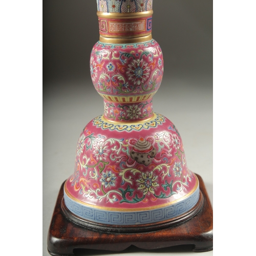 149 - A CHINESE PINK GROUND FAMILLE ROSE PORCELAIN SECTIONAL GU VASE, and fitted hardwood stand, bearing Q... 