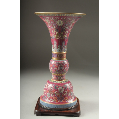 149 - A CHINESE PINK GROUND FAMILLE ROSE PORCELAIN SECTIONAL GU VASE, and fitted hardwood stand, bearing Q... 