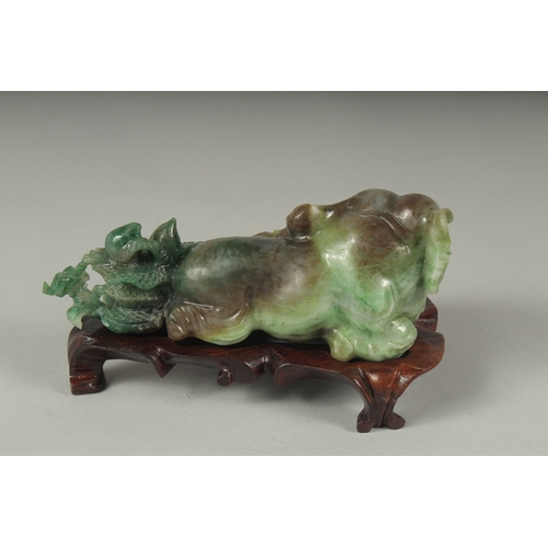 26 - A CHINESE CARVED JADE FIGURE OF AN ELEPHANT ON A FITTED CARVED HARDWOOD STAND, figure 14cm long.