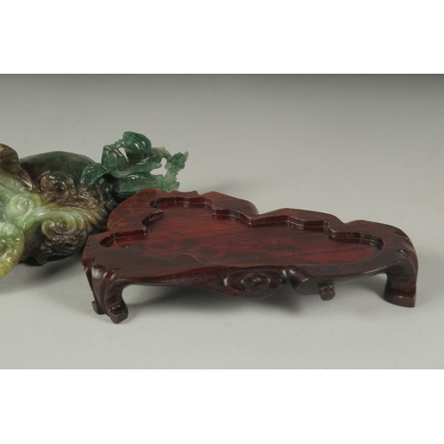 26 - A CHINESE CARVED JADE FIGURE OF AN ELEPHANT ON A FITTED CARVED HARDWOOD STAND, figure 14cm long.