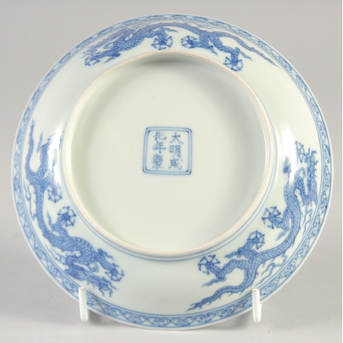 49 - A CHINESE BLUE AND WHITE PORCELAIN DISH, decorated with dragons, bearing six-character mark, 15cm di... 