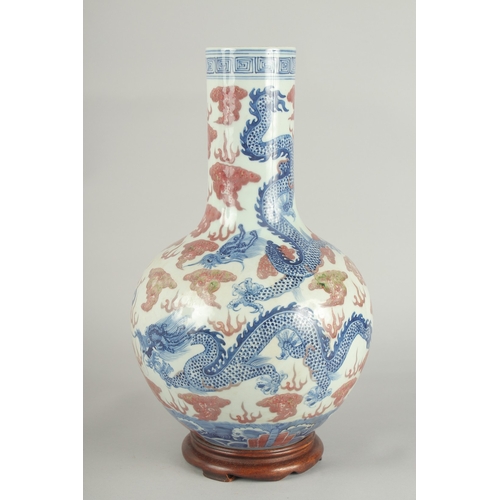 66 - A CHINESE UNDERGLAZE RED AND BLUE PORCELAIN DRAGON VASE ON HARDWOOD STAND, painted with three dragon... 