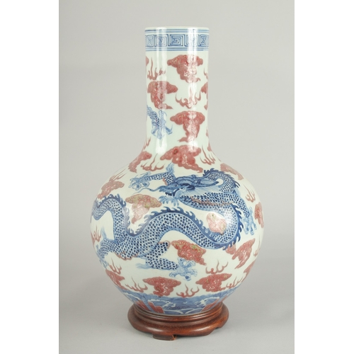 66 - A CHINESE UNDERGLAZE RED AND BLUE PORCELAIN DRAGON VASE ON HARDWOOD STAND, painted with three dragon... 