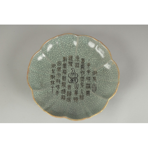 68 - A CHINESE CELADON CRACKLE GLAZE PETAL-RIM DISH, the centre with incised characters, 19cm wide.