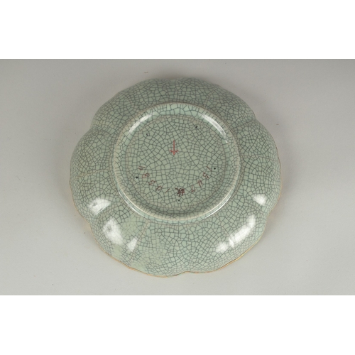 68 - A CHINESE CELADON CRACKLE GLAZE PETAL-RIM DISH, the centre with incised characters, 19cm wide.