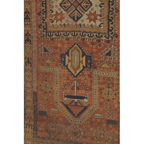 1002 - A PERSIAN RUG, rust ground with geometric stylised decoration. 7ft 7ins x 3ft 11ins.