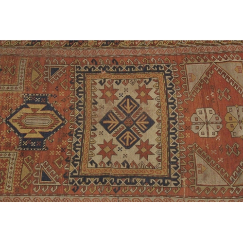 1002 - A PERSIAN RUG, rust ground with geometric stylised decoration. 7ft 7ins x 3ft 11ins.