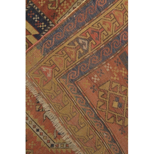 1002 - A PERSIAN RUG, rust ground with geometric stylised decoration. 7ft 7ins x 3ft 11ins.