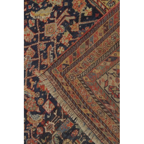 1003 - A PERSIAN RUG dark blue ground with stylised decoration. 7ft x 4ft 7ins.