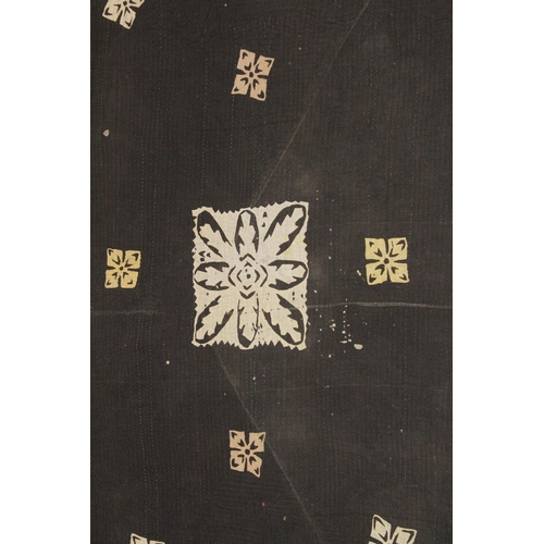 1006 - A QUILTED BEDSPREAD black ground with geometric designs. 7ft 4ins x 4ft 4ins.