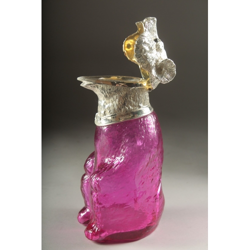 1046 - A GLASS CLARET JUG formed as a bear with silver plated head. 7ins high.