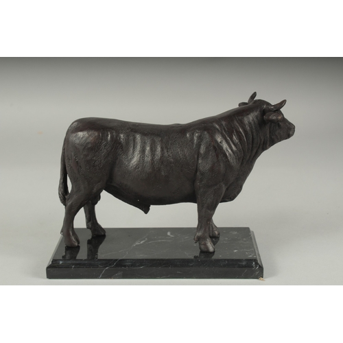 1102 - A BRONZE STANDING BULL on a marble base. 9ins long.