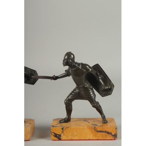 1115 - A GOOD PAIR OF 19TH CENTURY BRONZE FIGHTING SOLDIERS carrying a sword an shield, standing on a yello... 