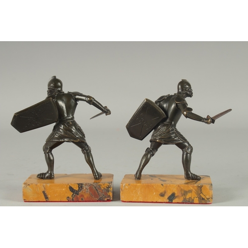 1115 - A GOOD PAIR OF 19TH CENTURY BRONZE FIGHTING SOLDIERS carrying a sword an shield, standing on a yello... 