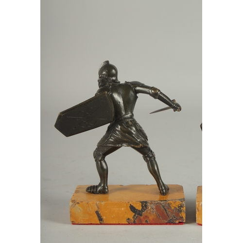 1115 - A GOOD PAIR OF 19TH CENTURY BRONZE FIGHTING SOLDIERS carrying a sword an shield, standing on a yello... 