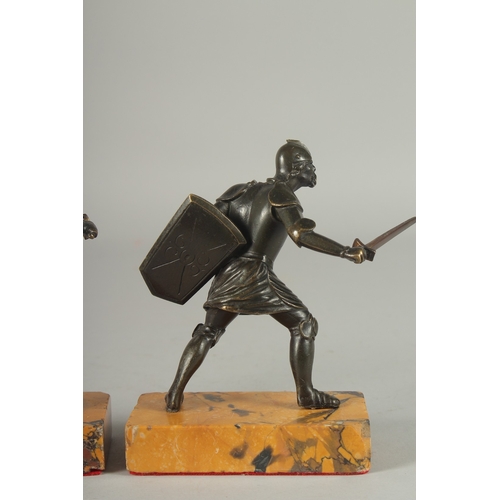 1115 - A GOOD PAIR OF 19TH CENTURY BRONZE FIGHTING SOLDIERS carrying a sword an shield, standing on a yello... 