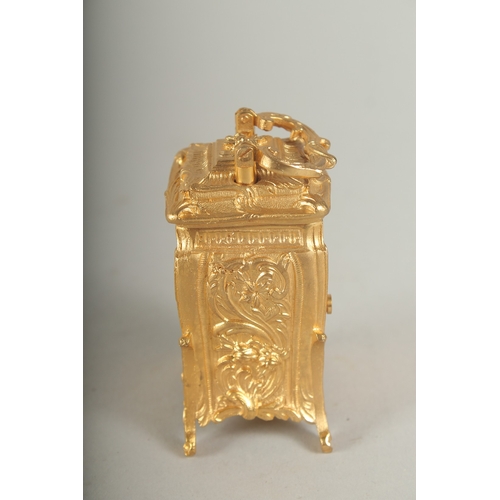 1128 - A SMALL GILDED CARRIAGE CLOCK with blue and white Roman numerals and carrying handles.  7cm high.