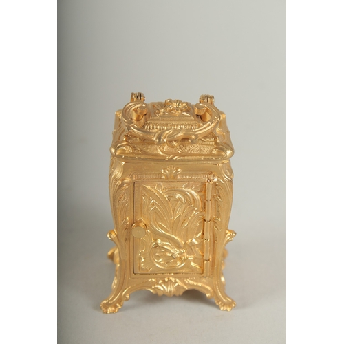 1128 - A SMALL GILDED CARRIAGE CLOCK with blue and white Roman numerals and carrying handles.  7cm high.