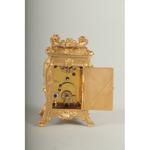 1128 - A SMALL GILDED CARRIAGE CLOCK with blue and white Roman numerals and carrying handles.  7cm high.