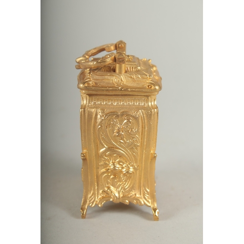 1128 - A SMALL GILDED CARRIAGE CLOCK with blue and white Roman numerals and carrying handles.  7cm high.