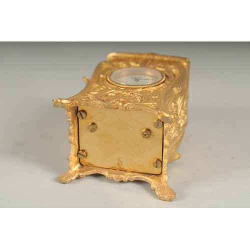 1128 - A SMALL GILDED CARRIAGE CLOCK with blue and white Roman numerals and carrying handles.  7cm high.