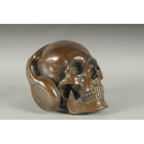 1193 - A BRONZE SKULL wearing headphones. 7ins high.