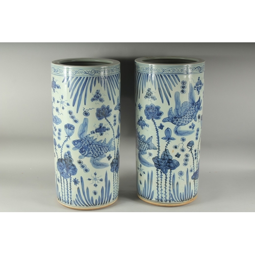 1219 - A PAIR OF CHINESE BLUE AND WHITE UMBRELLA STANDS decorated with carp.  23ins high.