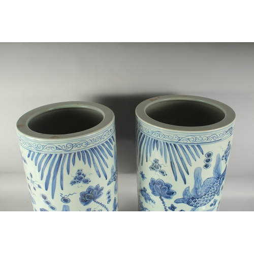 1219 - A PAIR OF CHINESE BLUE AND WHITE UMBRELLA STANDS decorated with carp.  23ins high.