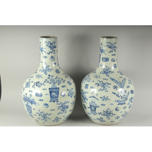 1220 - A PAIR OF CHINESE BLUE AND WHITE VASES decorated with emblems. 22ins high.