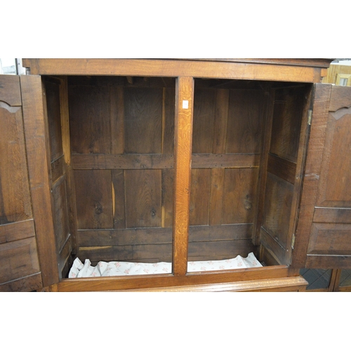 338 - A George III oak linen press with a pair of panel doors above dummy drawers and three real drawers (... 