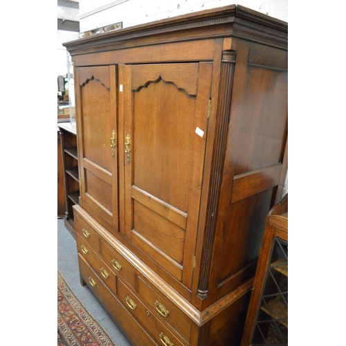 338 - A George III oak linen press with a pair of panel doors above dummy drawers and three real drawers (... 