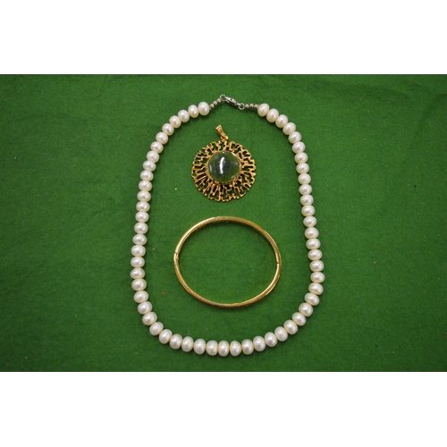 935 - A gilt metal bangle, pearl necklace and a gilt metal pendant.