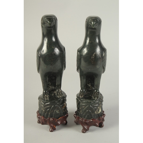 113 - A PAIR OF CHINESE CARVED DARK GREEN HARDSTONE BIRDS, mounted to fitted carved hardwood stands raised... 