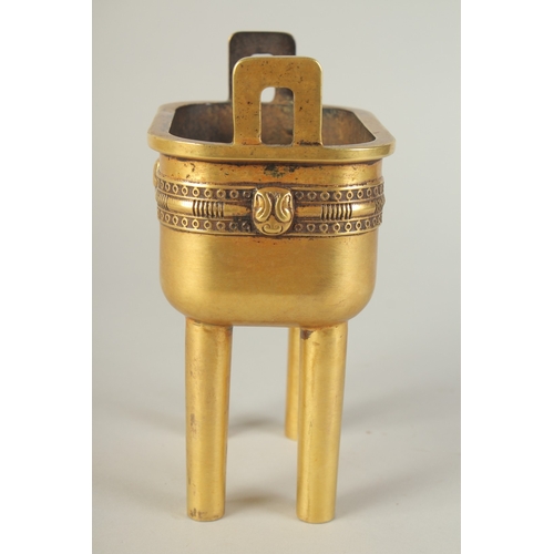 114 - A CHINESE HEAVY GILDED BRONZE TWIN HANDLE CENSER, raised on four tall legs, the base with character ... 